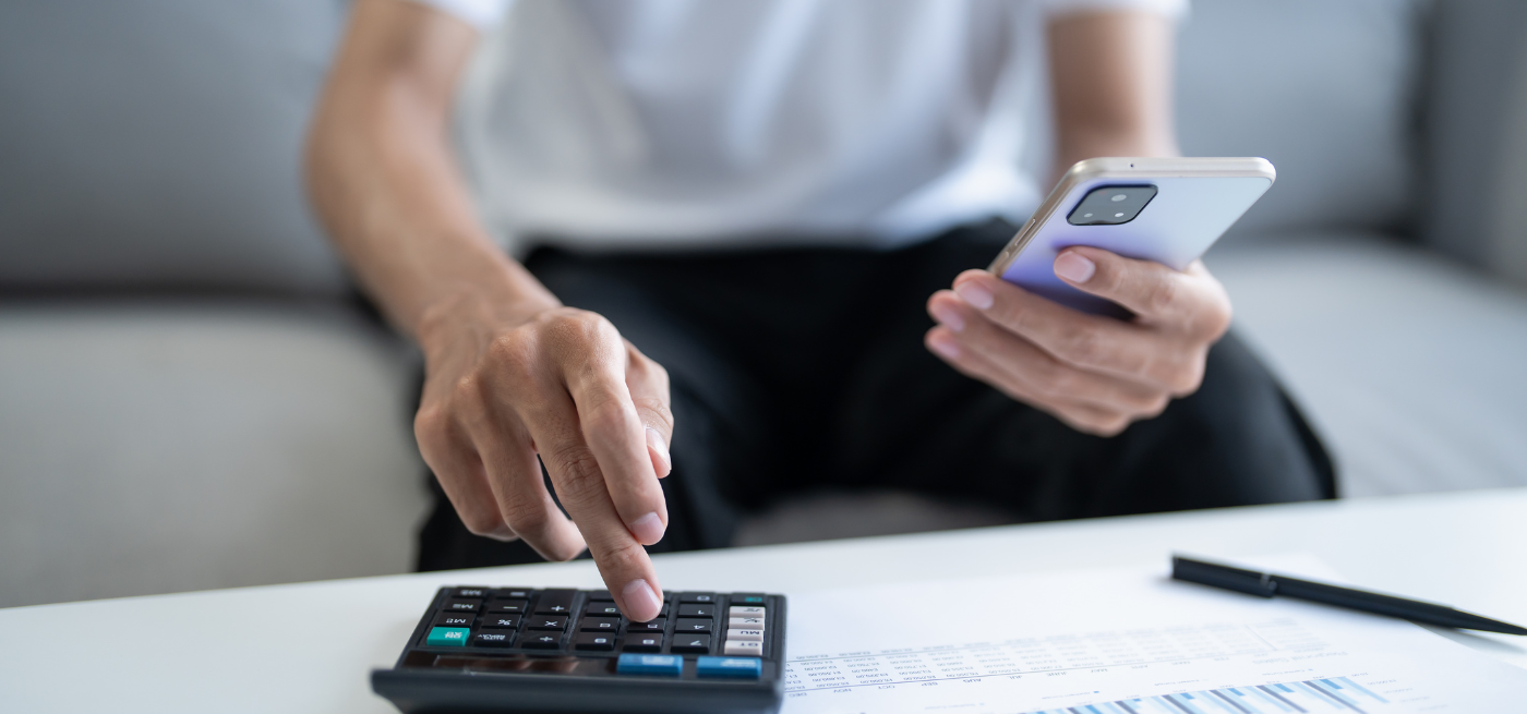 Pessoa a usar calculadora e telemóvel para analisar valores da prestação do crédito habitação